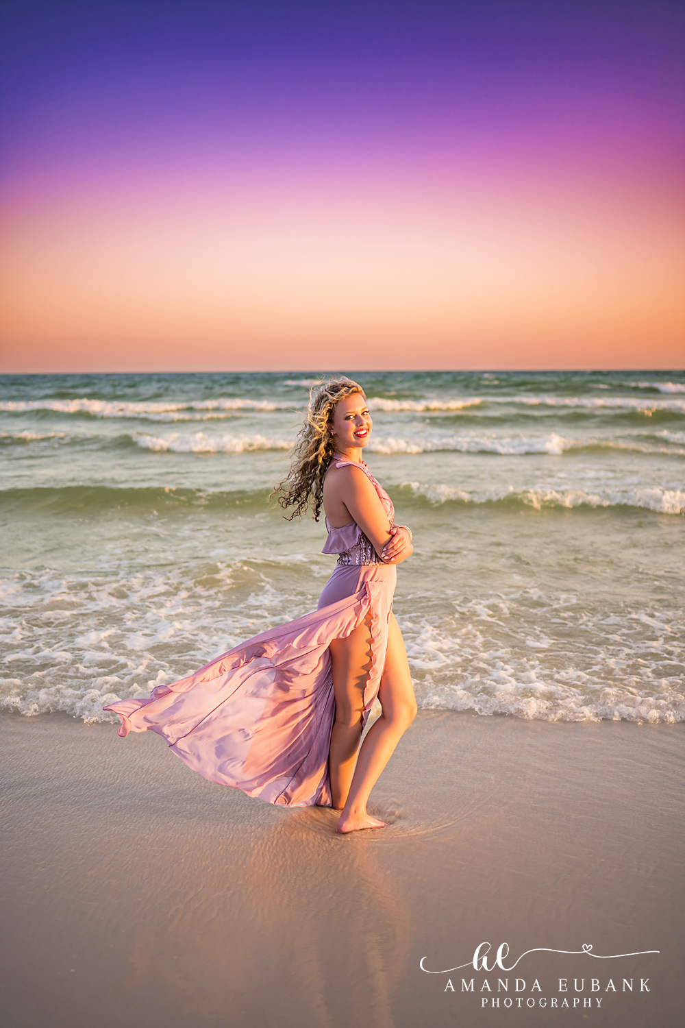 Sandestin Senior Photographer – Walking Through the Sunset Surf Senior in a pink dress walking through shallow ocean waves at sunset in Sandestin, Florida
