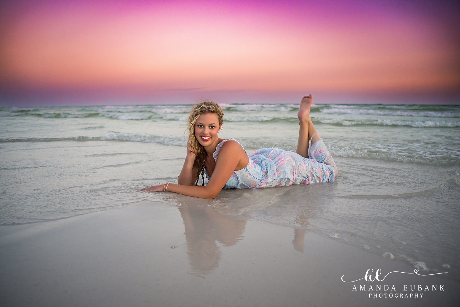 Sandestin Senior Photographer – Reclining on the Shore at Sunset High school senior lying on the beach in a blue floral dress at sunset in Sandestin, Florida