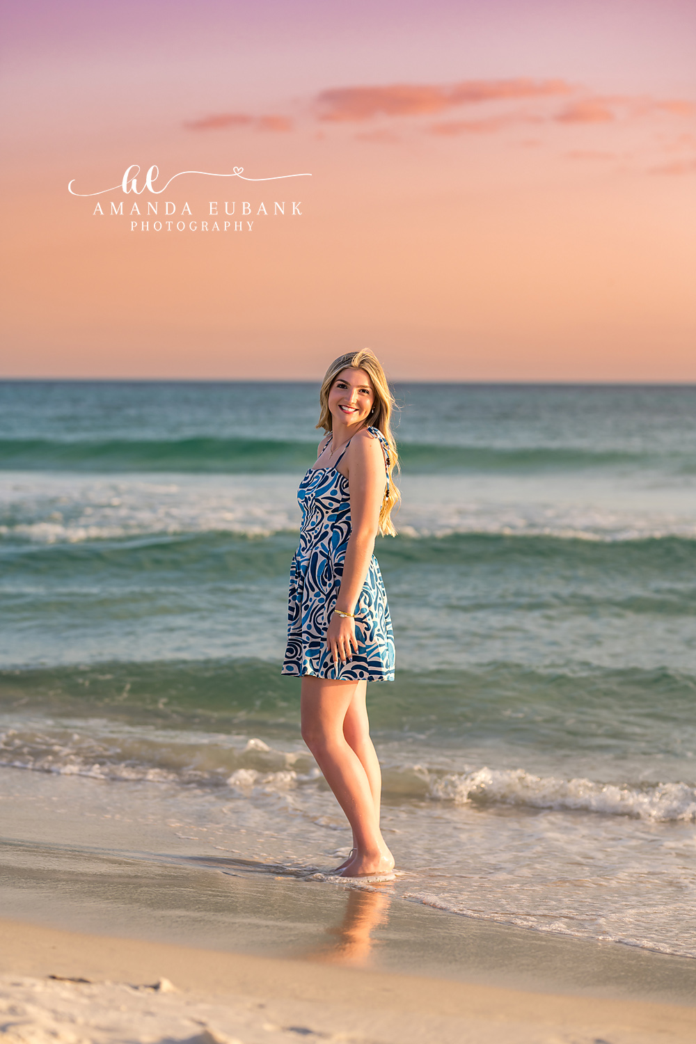 Santa Rosa Beach Senior Session – Standing in the Emerald Surf High school senior in a blue patterned dress standing in the shallow emerald surf at sunset during a Santa Rosa Beach senior photography session