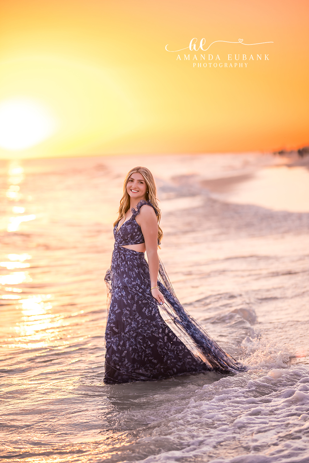 Santa Rosa Beach Senior Session – Navy Floral Gown in the Surf High school senior in a navy floral two-piece gown standing in the surf at sunset during a Santa Rosa Beach senior photography session
