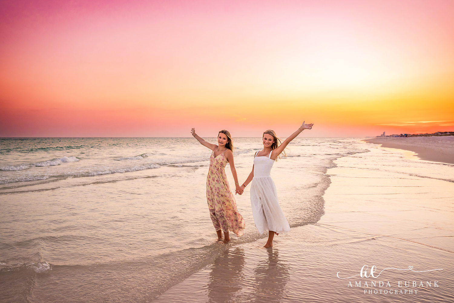 WaterSound Beach Sunset Family Session – Sisters Walking on the Shore Two women walking hand in hand along the shoreline at sunset during a WaterSound Beach family photography session