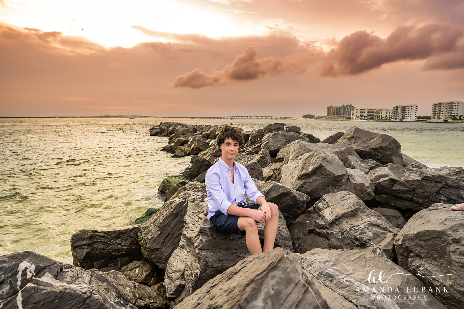 Destin Jetties Family Photos | Boy sitting A boy sitting on the rocks at the Destin Jetties in Destin, Florida at sunset, photographed by Destin family photographer Amanda Eubank