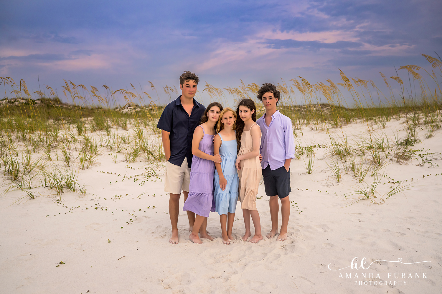 Destin Jetties Family Photos | Family group standing together A family group standing together among the sea oats and dunes near the Destin Jetties in Destin, Florida at sunset, photographed by Destin family photographer Amanda Eubank