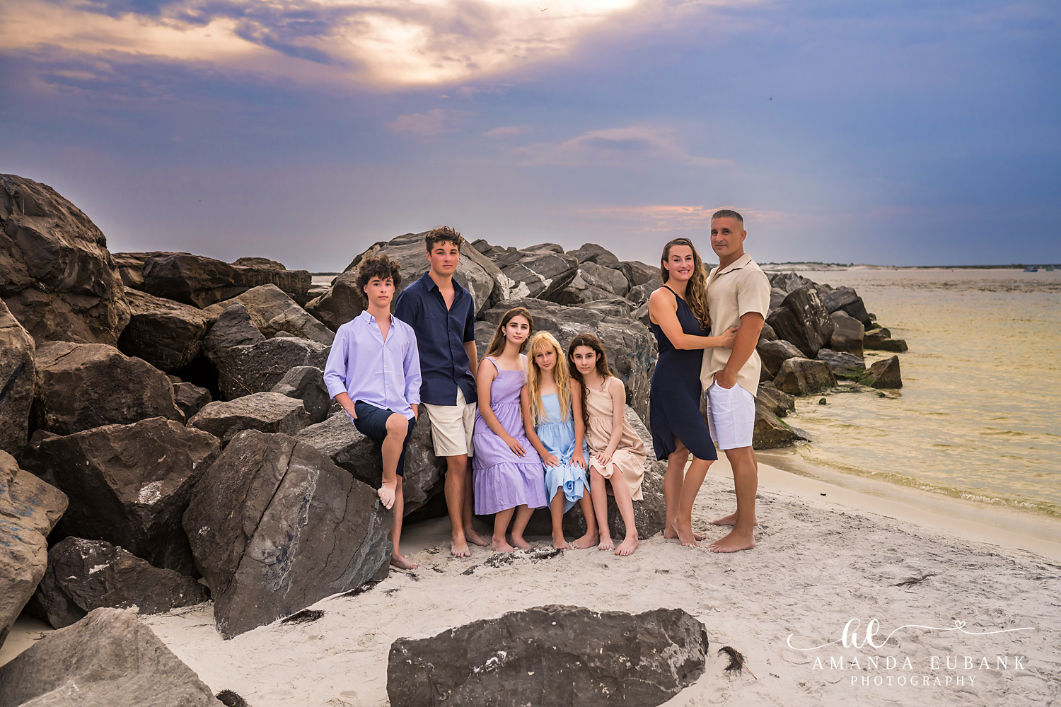 Destin Jetties Family Photos | Family group posed on the sand A family group posed on the sand on the sand beside the Destin Jetties in Destin, Florida at sunset, photographed by Destin family photographer Amanda Eubank