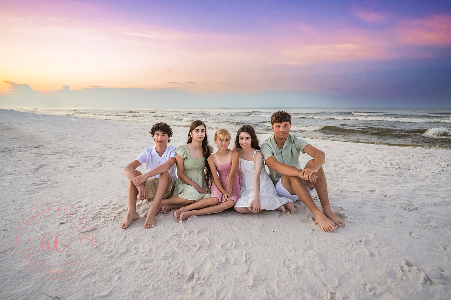 Miramar Beach Sunrise Family Photos | Siblings sitting together in the sand Siblings sitting together in the sand on the beach in Miramar Beach, Florida at sunrise, photographed by Miramar Beach family photographer Amanda Eubank