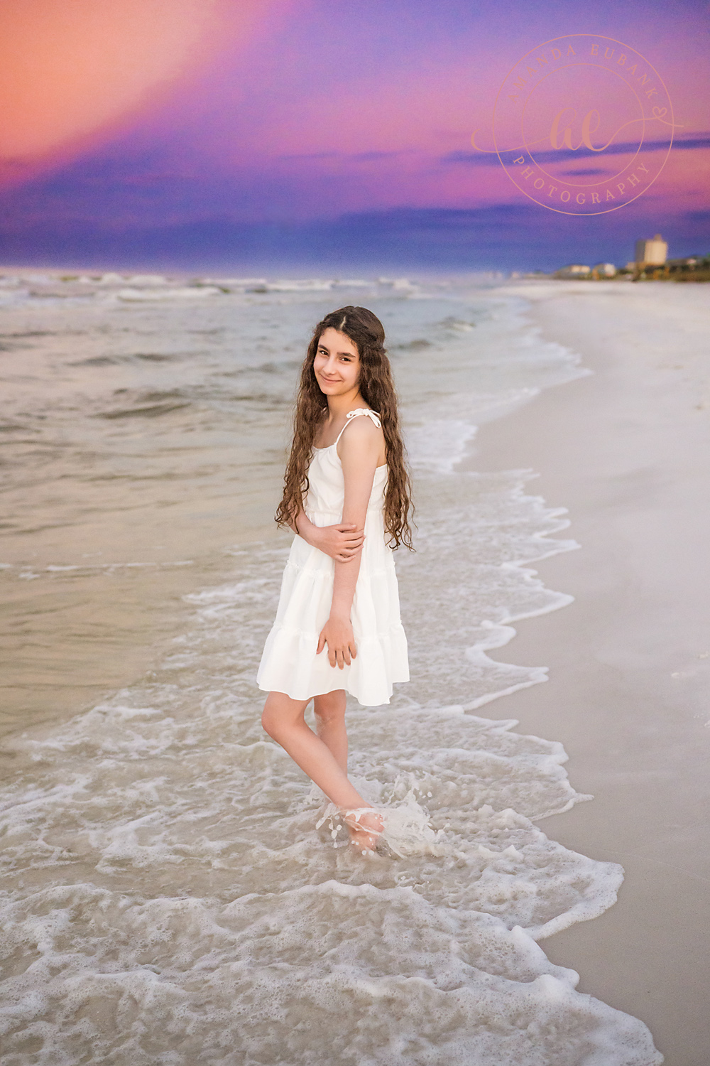 Miramar Beach Sunrise Family Photos | Teen girl in a white dress walking through the surf A teen girl in a white dress walking through the surf on the beach in Miramar Beach, Florida at sunrise, photographed by Miramar Beach family photographer Amanda Eubank