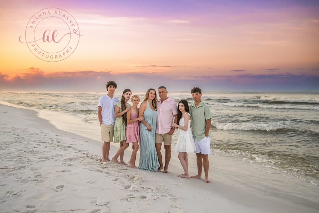A family lined up along the shoreline on the beach in Miramar Beach, Florida at sunrise, photographed by Miramar Beach family photographer Amanda Eubank