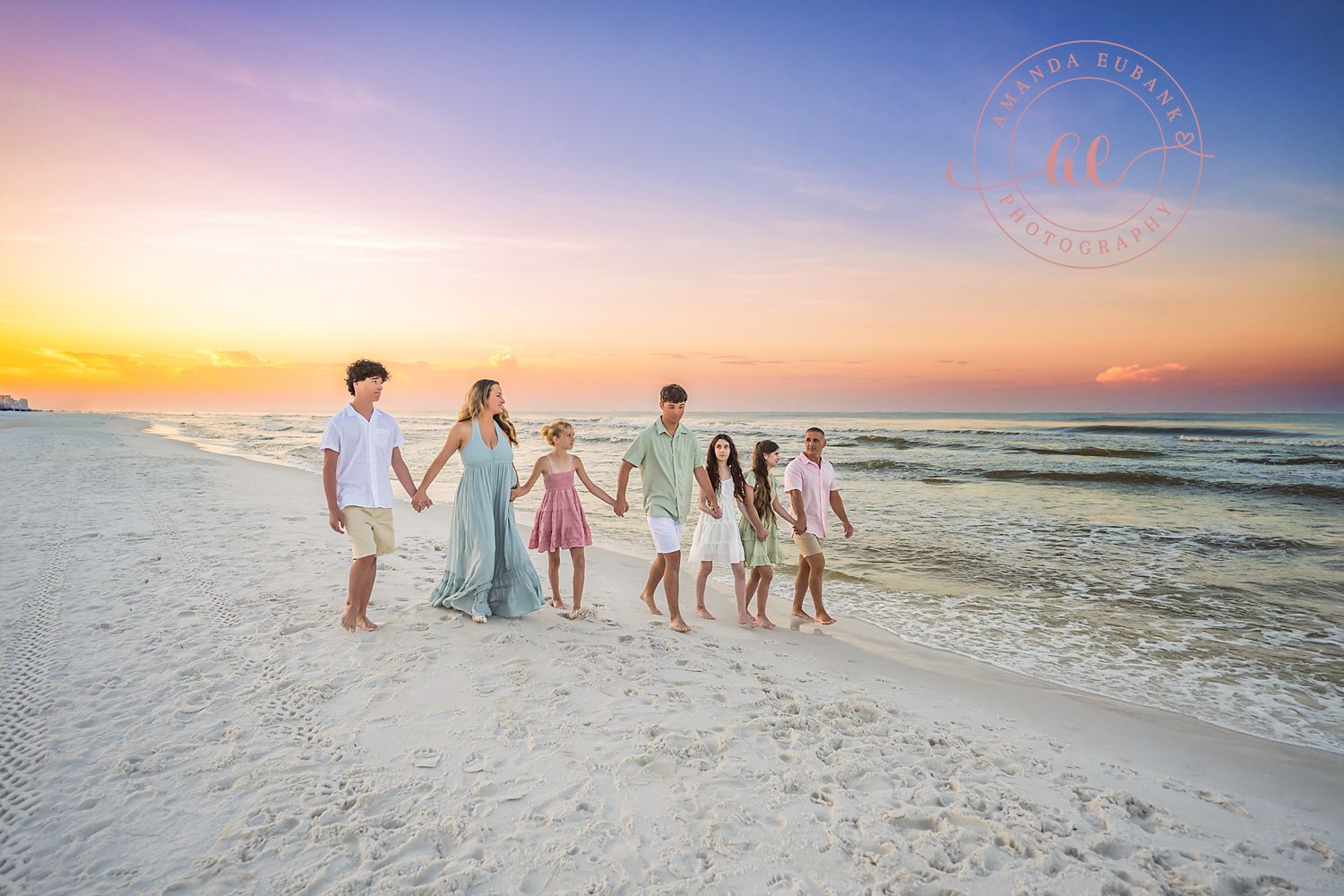 Miramar Beach Sunrise Family Photos | Family walking hand in hand A family walking hand in hand on the beach in Miramar Beach, Florida at sunrise, photographed by Miramar Beach family photographer Amanda Eubank
