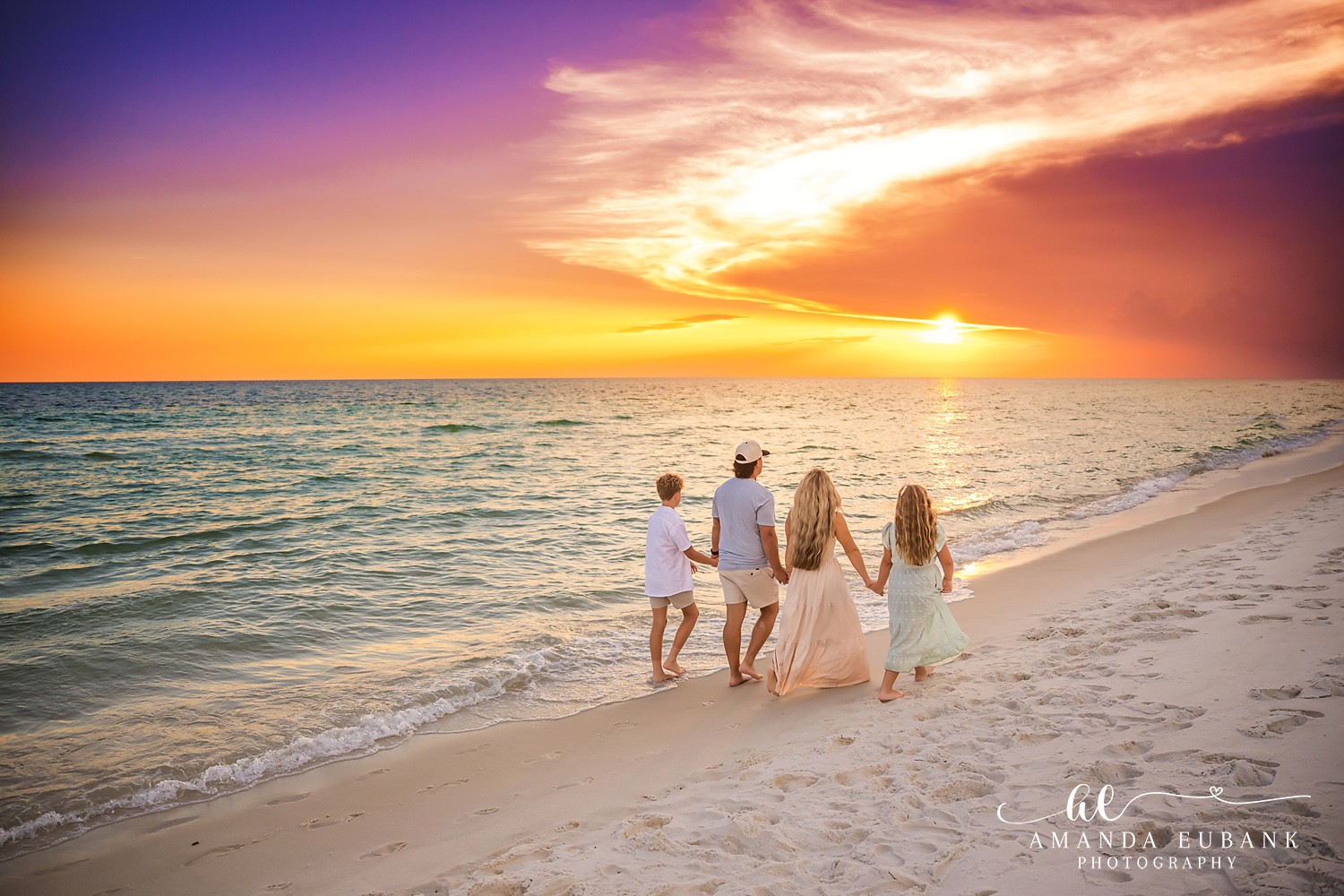 Rosemary Beach Family Photos | Family of four walking hand in hand A family of four walking hand in hand on the beach in Rosemary Beach, Florida at sunset, photographed by Rosemary Beach family photographer Amanda Eubank