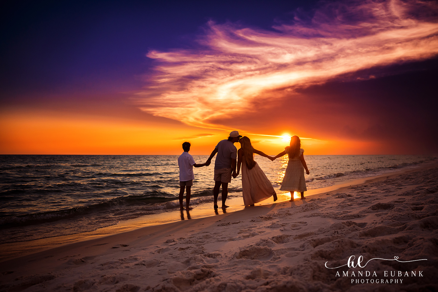 A family silhouette holding hands on the beach in Rosemary Beach, Florida at sunset, photographed by Rosemary Beach family photographer Amanda Eubank