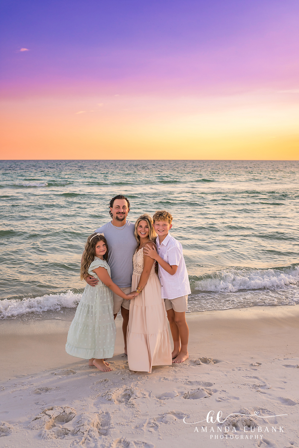 Rosemary Beach Family Photos | Family of four standing together A family of four standing together on the beach in Rosemary Beach, Florida at sunset, photographed by Rosemary Beach family photographer Amanda Eubank