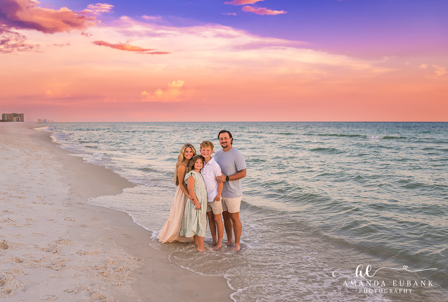 Rosemary Beach Family Photos | Family of four under pink clouds A family of four under pink clouds on the beach in Rosemary Beach, Florida at sunset, photographed by Rosemary Beach family photographer Amanda Eubank