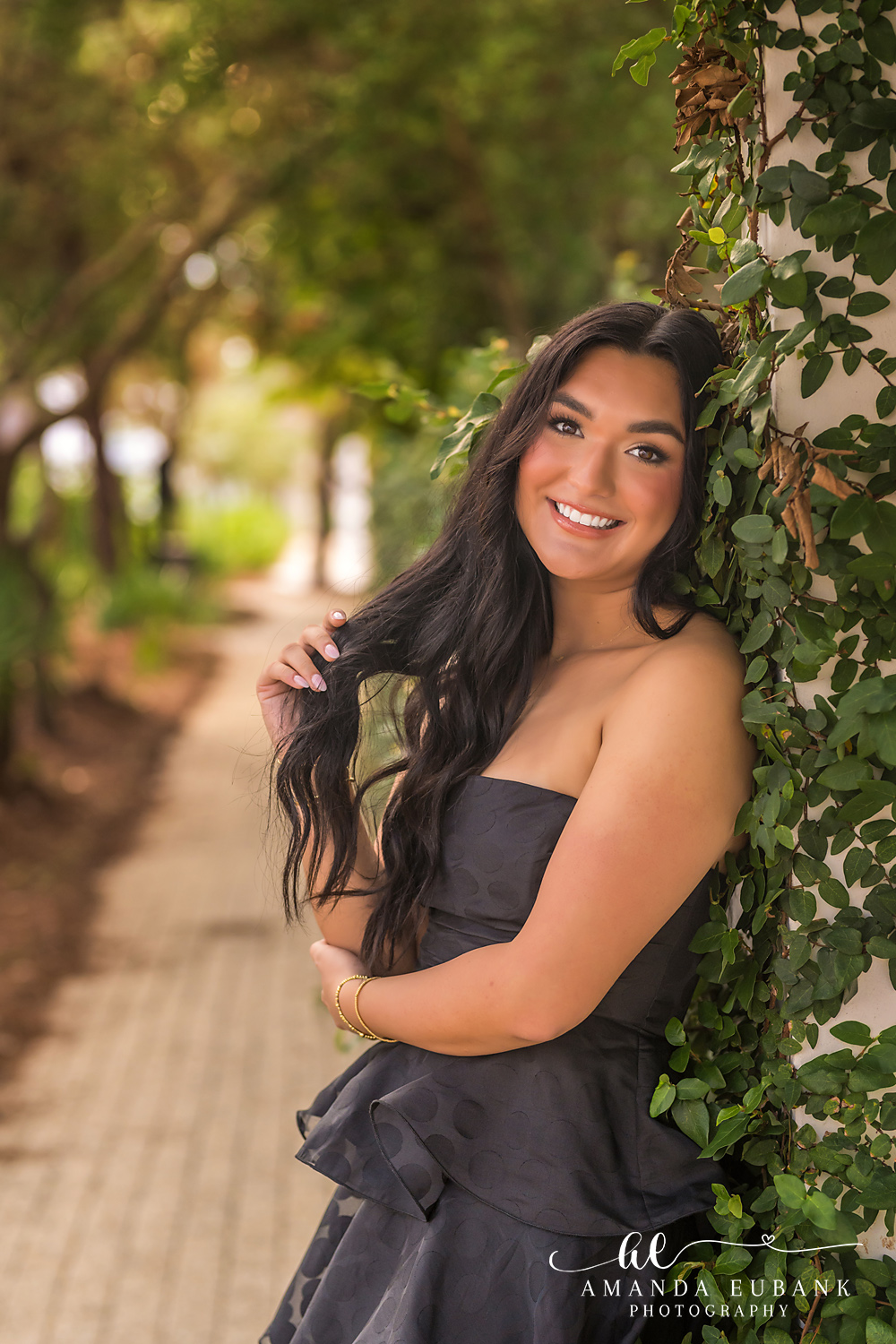 Rosemary Beach Senior Photos | Close portrait against ivy Rosemary Beach senior photographer: close up senior portrait of a girl in a black strapless dress with hand in her long dark hair against an ivy wall
