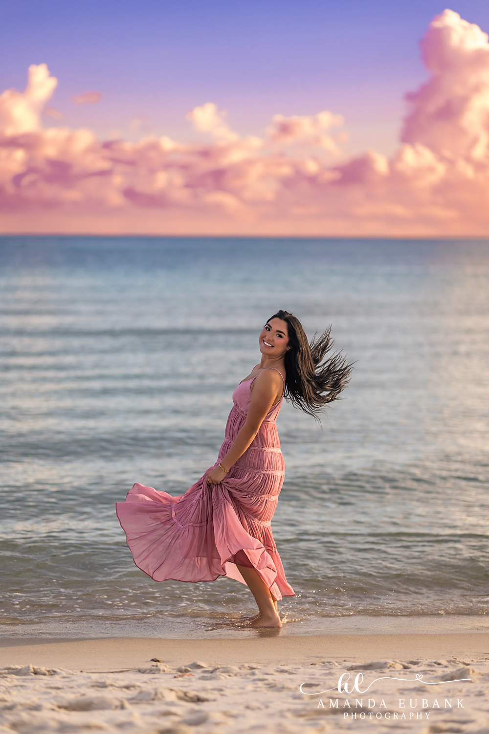 Rosemary Beach Senior Photos | Hair flip at the shoreline Rosemary Beach senior photographer: senior girl in a pink dress with hair and skirt in motion at the shoreline under pink clouds