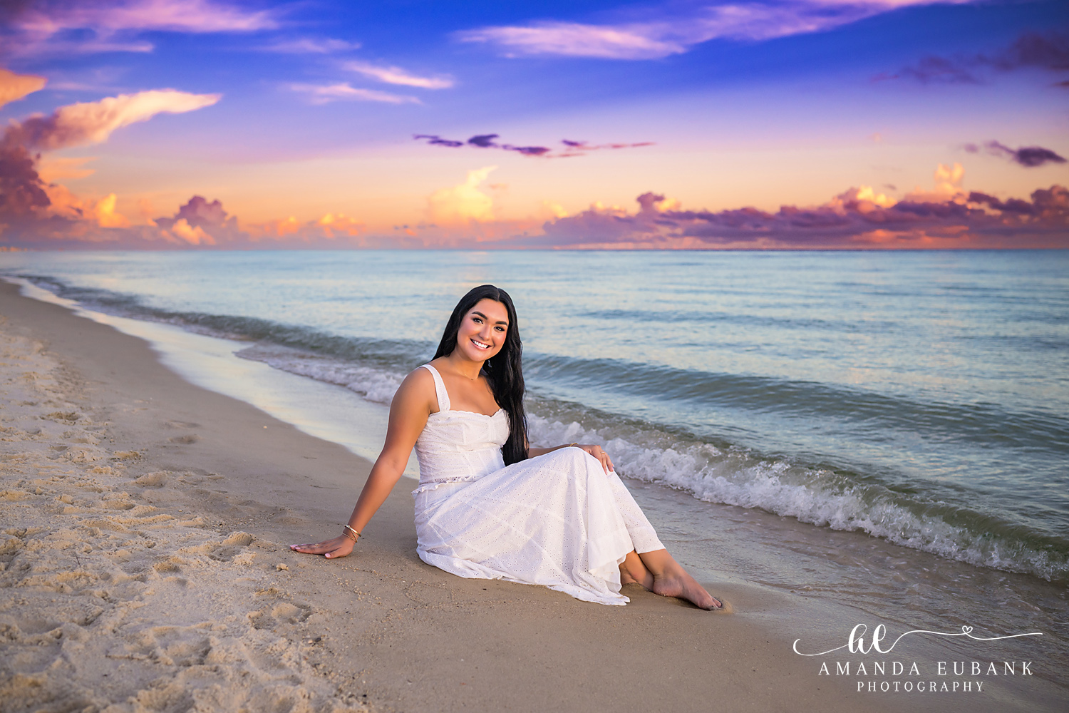 Rosemary Beach Senior Photos | Reclining at the water’s edge Rosemary Beach senior photographer: senior girl in a white dress reclining on the sand at the water's edge with waves and a colorful sky