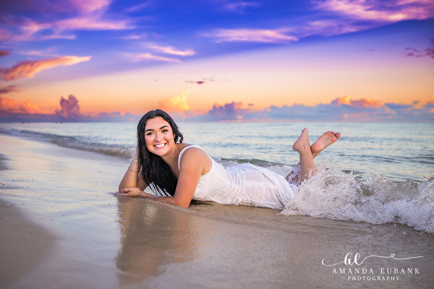 Rosemary Beach Senior Photos | Splash at the shoreline Rosemary Beach senior photographer: senior girl in a white dress lying on the wet sand with feet up as a wave splashes behind her