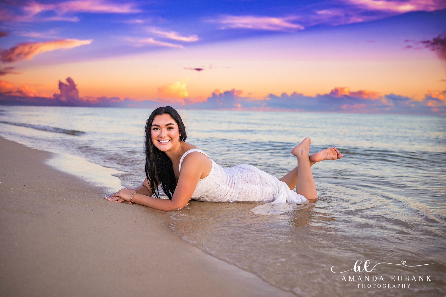 Rosemary Beach Senior Photos | Lying at the shoreline Rosemary Beach senior photographer: senior girl in a white dress lying on the wet sand at the water's edge with feet up under a colorful sky